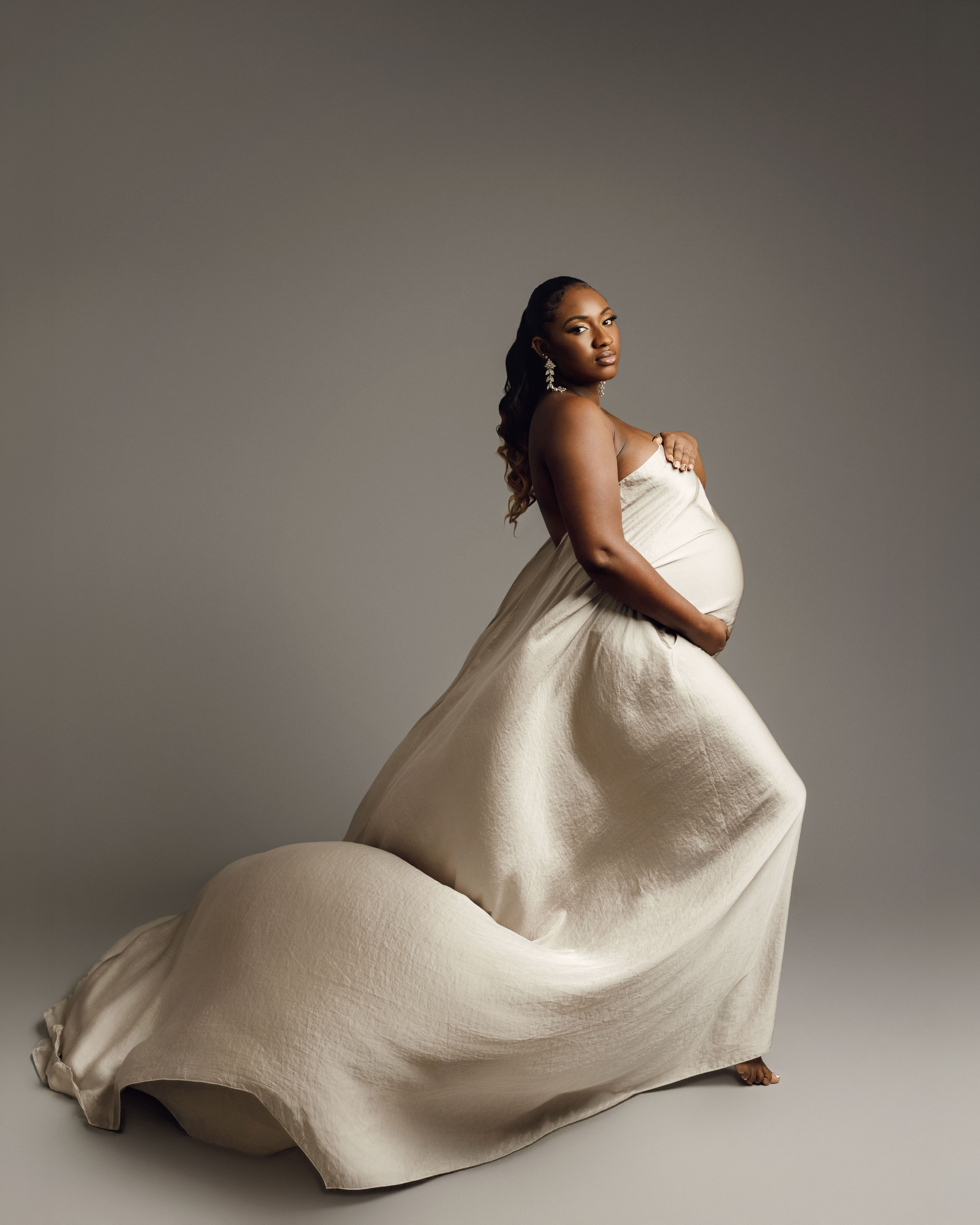 Maternity photoshoot London – elegant studio portrait of pregnant woman in flowing neutral dress