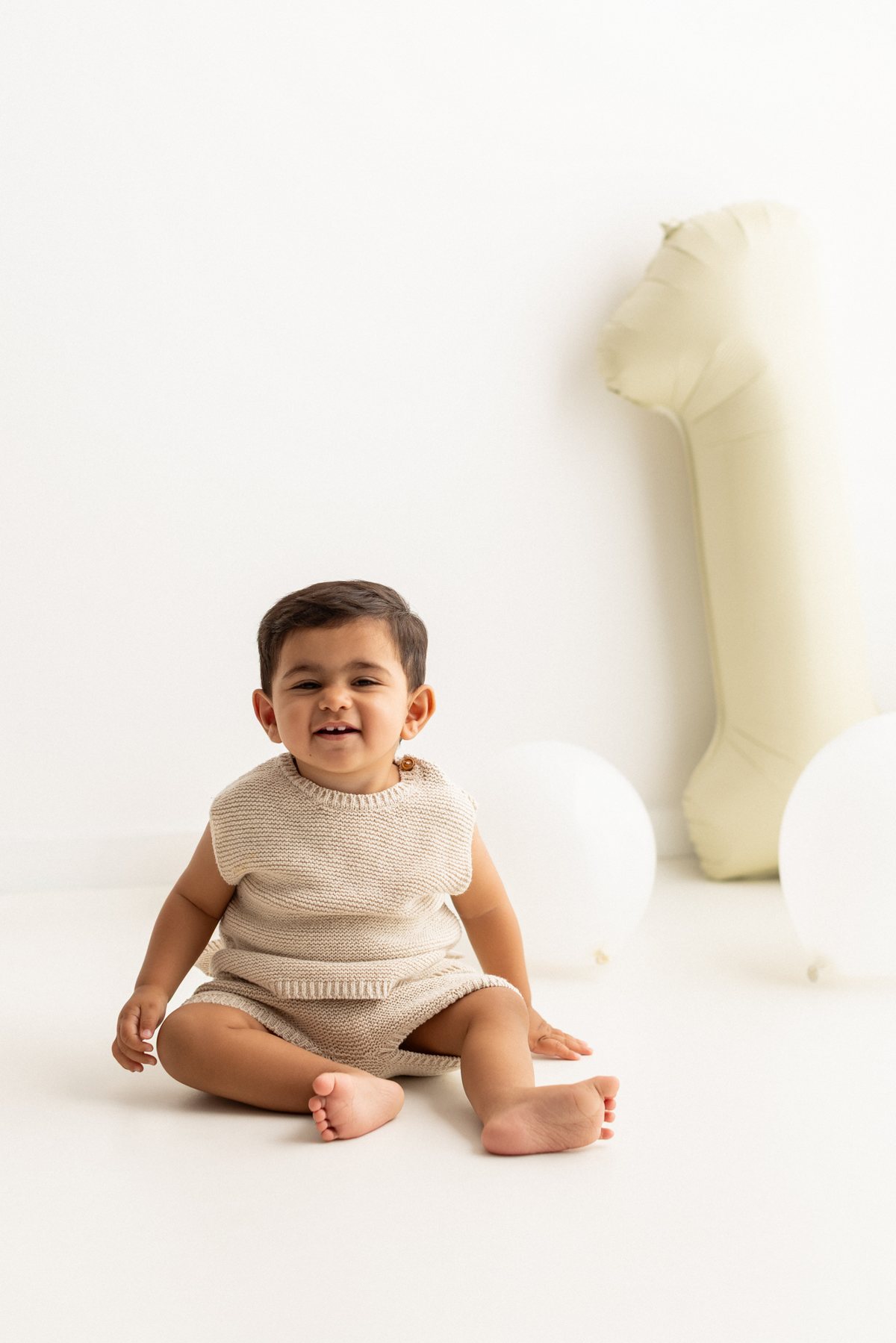 Laughing baby with a number 1 balloon at a Birthday Mini Session in Barking