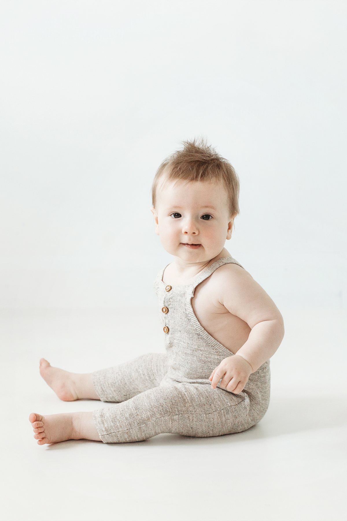 Baby sitting up in a knitted romper at a Milestone Mini Session in Barking